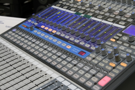 Professional audio operator working on audio mixer knobs during live TV telecastの写真素材