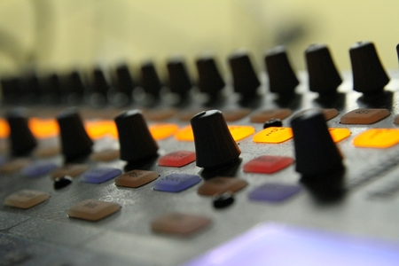 Professional audio operator working on audio mixer knobs during live TV telecastの写真素材