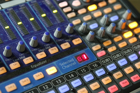 Professional audio operator working on audio mixer knobs during live TV telecastの写真素材