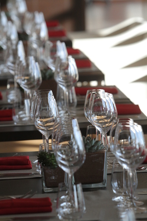 Sun light illuminates a wooden table full of empty glasses.の写真素材