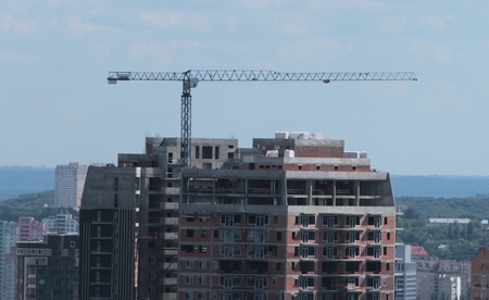 Building crane and building under construction against blue sky.の写真素材