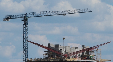 Building crane and building under construction against blue sky.の写真素材