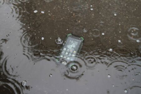 Mobile phones on the sand under the water.の写真素材