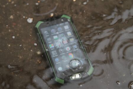 Mobile phones on the sand under the water.の写真素材