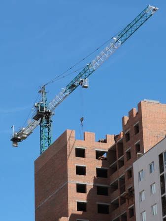 Building crane and building under construction against blue skyの写真素材