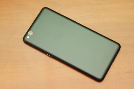 Black smartphone lying on a wooden tableの写真素材