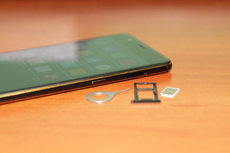 Black smartphone lying on a wooden table.の写真素材
