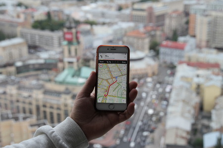 Hand using smartphone searching location on satellite navigation application and network connection over traffic transportation in Kiev, Ukraine, 30.08.2017.の写真素材