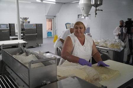 Production of bakery products in a bakery. The baker kneads the dough for baking buns.のeditorial素材