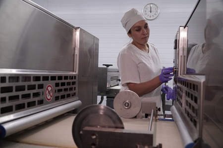 Production of bakery products in a bakery. The baker kneads the dough for baking buns.のeditorial素材