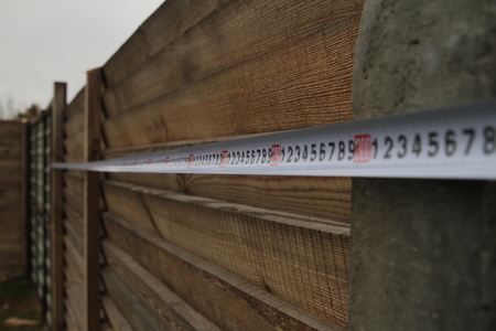 Measurement of a fence with a construction tape measure in the suburban area.の写真素材
