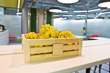 Bunches of grapes in a wooden box on a table in the kitchenの写真素材