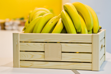 Bananas in a wooden box on the table in the kitchenの写真素材