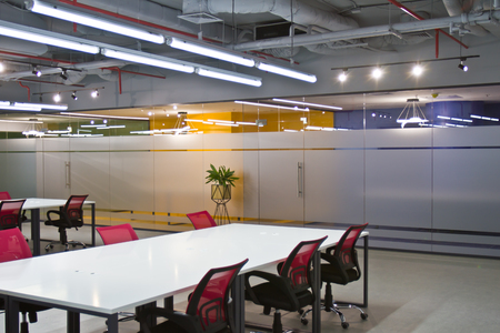Luxurious office space with large white tables and chairs and modern design. Conference room interior with empty chairs and a projector screen.の写真素材
