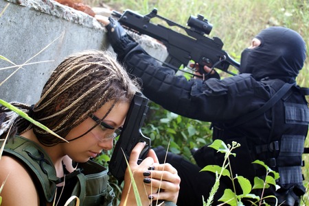 Two military men in a uniform: the man and the woman. In operation with the weapon. An aiming.の写真素材