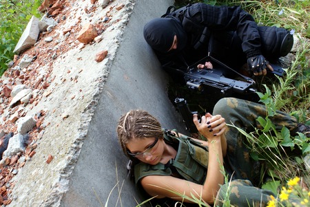 Two military men in a uniform: the man and the woman. In operation with the weapon. An aiming.の写真素材