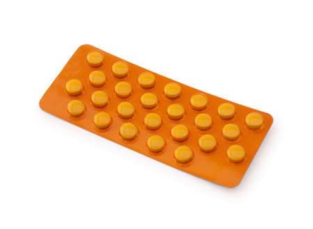 Orange medicine pills in a blister pack on a white backgroundの写真素材