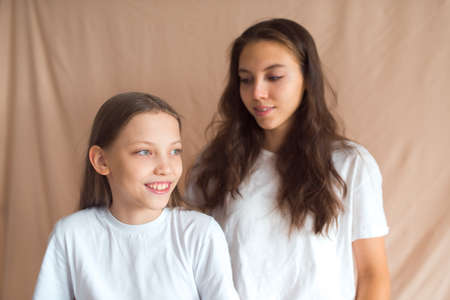 sisters having fun on beige color textile backgroundの写真素材