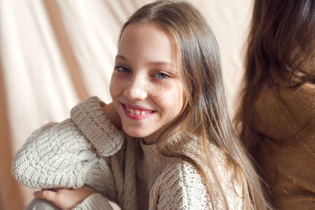 beautiful teenage girl with golden freckles on face posing on beige backgroundの写真素材