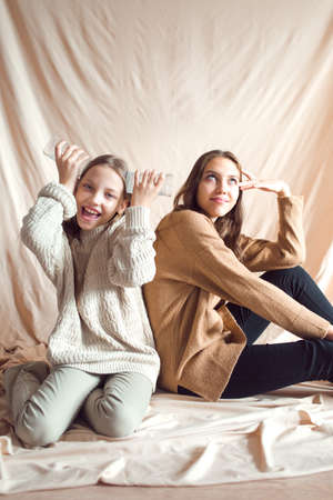 sisters having fun on beige color textile backgroundの写真素材