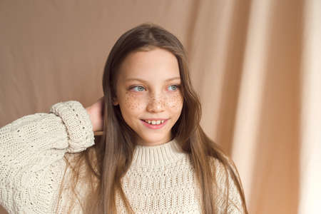 beautiful teenage girl with golden freckles on face posing on beige backgroundの写真素材