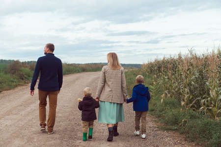 family walking countryside road near corn field at autumnの写真素材