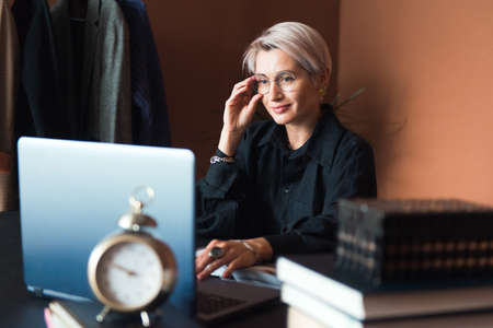 fashion woman in black shirt working in modern work place or office with laptopの写真素材