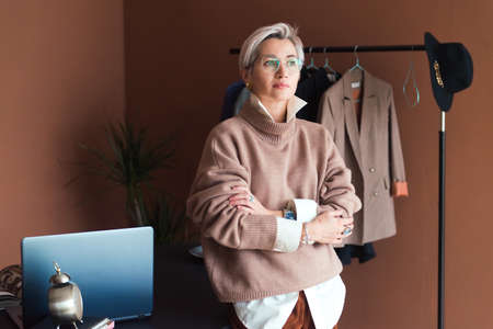 fashion woman in brown oversize sweater and trousers standing in modern work place or officeの写真素材