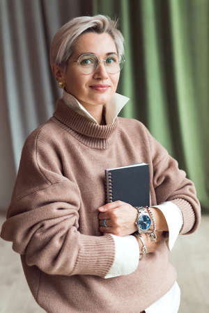 fashion woman in brown oversize sweater and trousers standing in modern work place or officeの写真素材