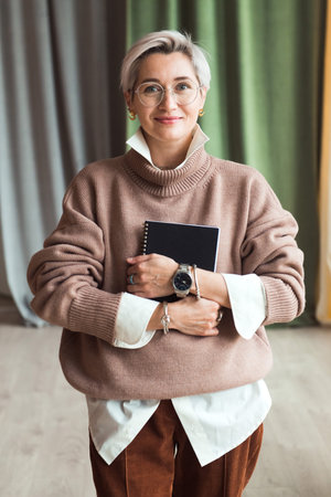 fashion woman in brown oversize sweater and trousers standing in modern work place or office