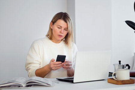 woman freelancer online working at table using smartphone