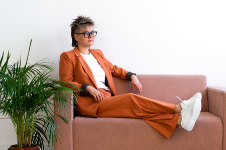fashion business woman queer portrait, sitting on couchの写真素材