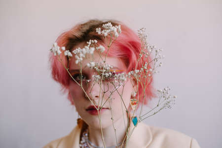 Young fashion stylish woman posing with gypsophila branch, bright make up and colored hairの写真素材