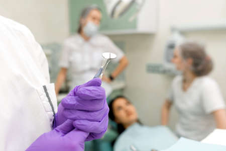 stomatologist hand in rubber gloves taking professional medical instrument for patient examinationの写真素材
