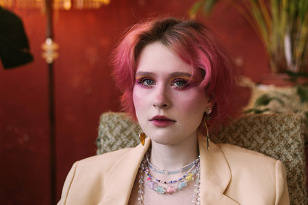 Young fashion stylish woman sitting on chair vintage studio, bright make up and colored hair,...