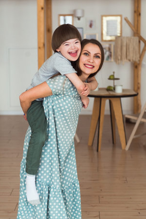 Loving mother holding piggy back boy with Down syndromeの写真素材