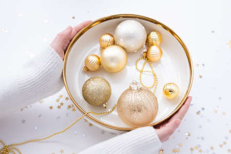 person holding new year decorations golden color with confetti on white backgroundの写真素材