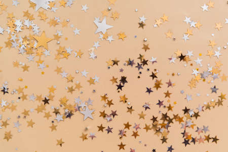 golden confetti stars on beige background top viewの写真素材
