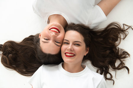Two beautiful women twin sisters close-up face portrait, laying on floor