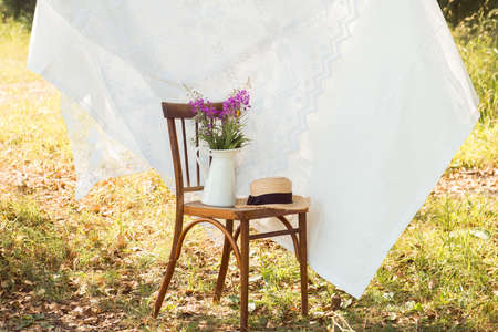 photo zone for outdoors photoshoot with vintage chair, cloth, flower vase and straw hatの写真素材