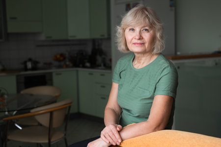 portrait of aged beautiful smiling woman sitting at home, looking at cameraの写真素材