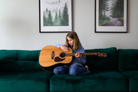 Little blond hair child playing the guitar at homeの写真素材