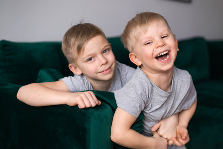 happy boys brothers posing on sofa at homeの写真素材