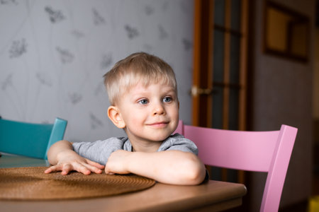 cute litlle boy sitting at the kitchen tableの写真素材