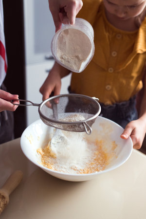 Making cookies at home, two girls cooking together, put flour in bowlの写真素材