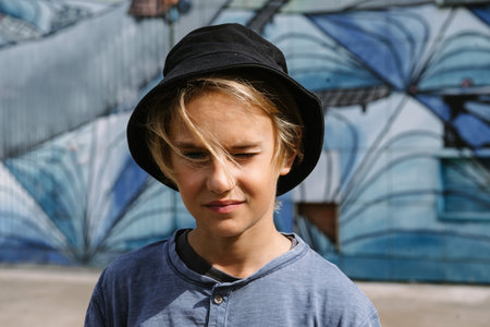 handsome teenage boy in hat osing at urban graffiti waal in hatの写真素材
