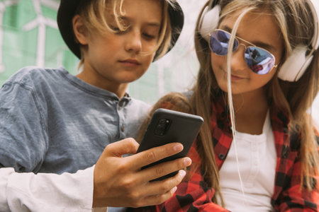 teenage boy and girl outdoors portrait, communicating and looking at smartphoneの写真素材