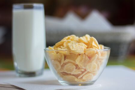 Corn flakes in transparent bowl on white tableの写真素材