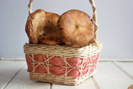 forest mushrooms in straw basket on white wooden tableの写真素材
