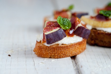 Bruschetta with goat cheese and figs on white tableの写真素材